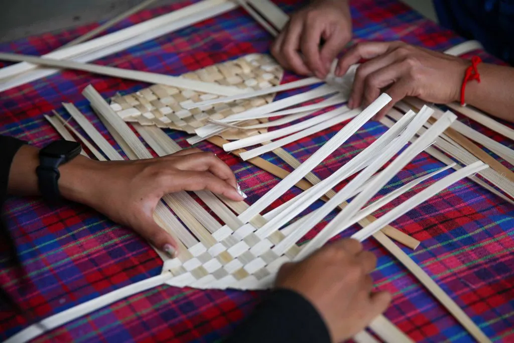 Hands weaving an unfinished bamboo fan / มือกำลังสานพัดไม้ไผ่ที่ยังไม่เสร็จ